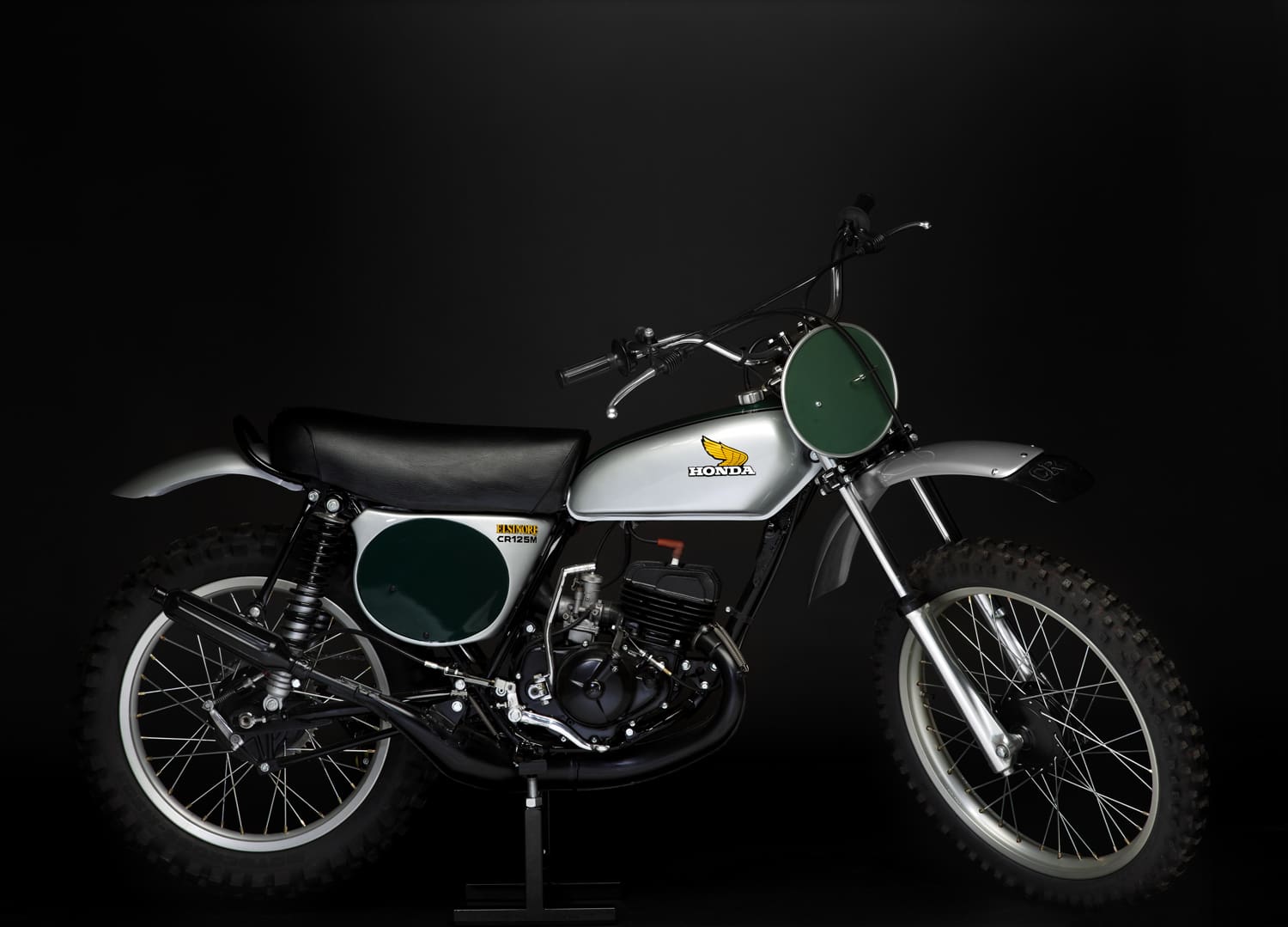 A white and green dirt bike on a black background.