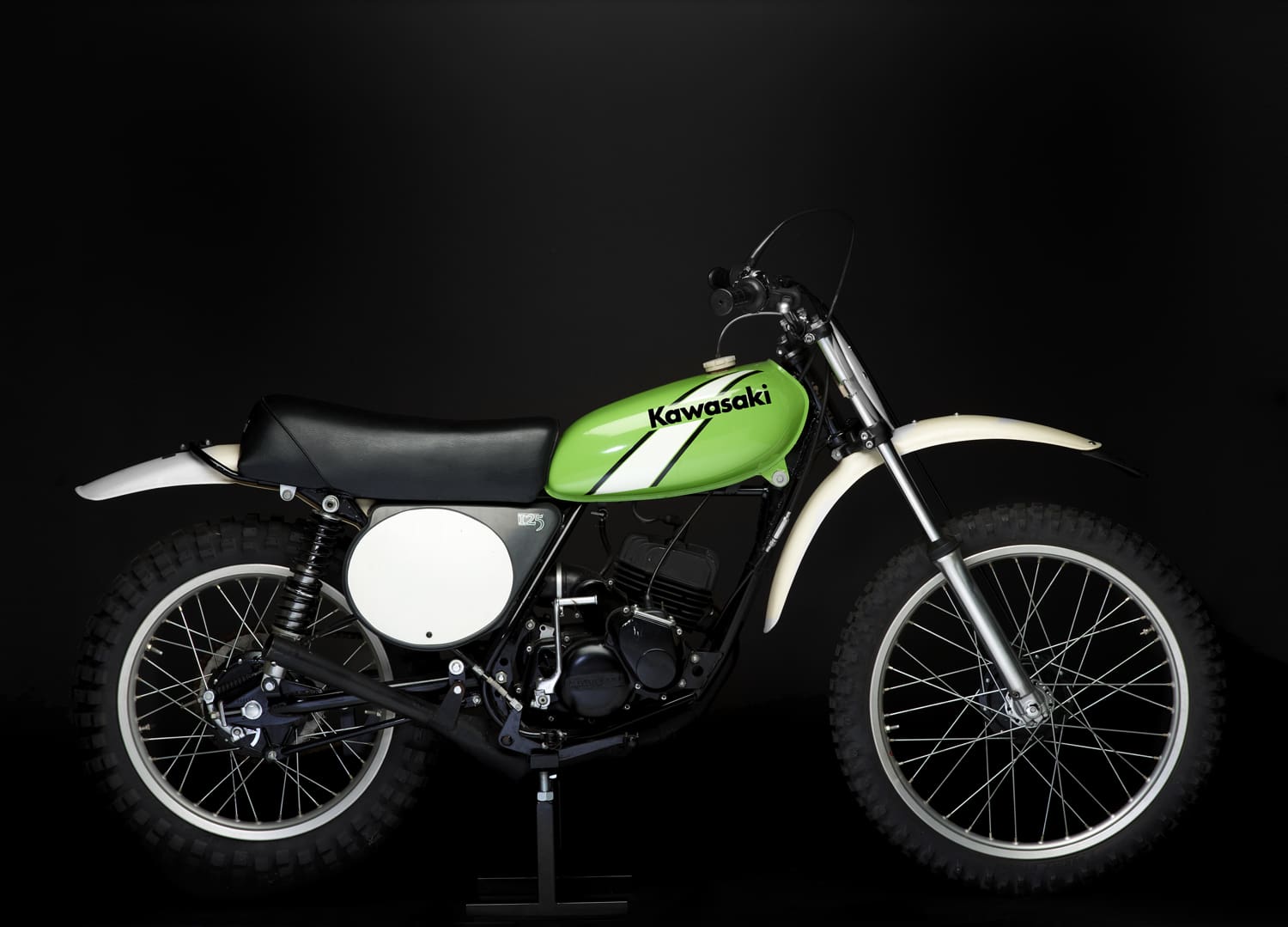 A green dirt bike is on display against a black background.