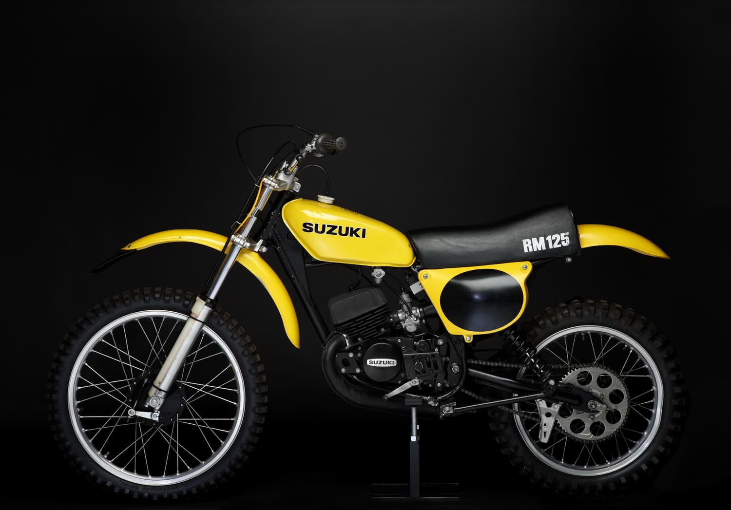 A yellow dirt bike sitting on a black background.