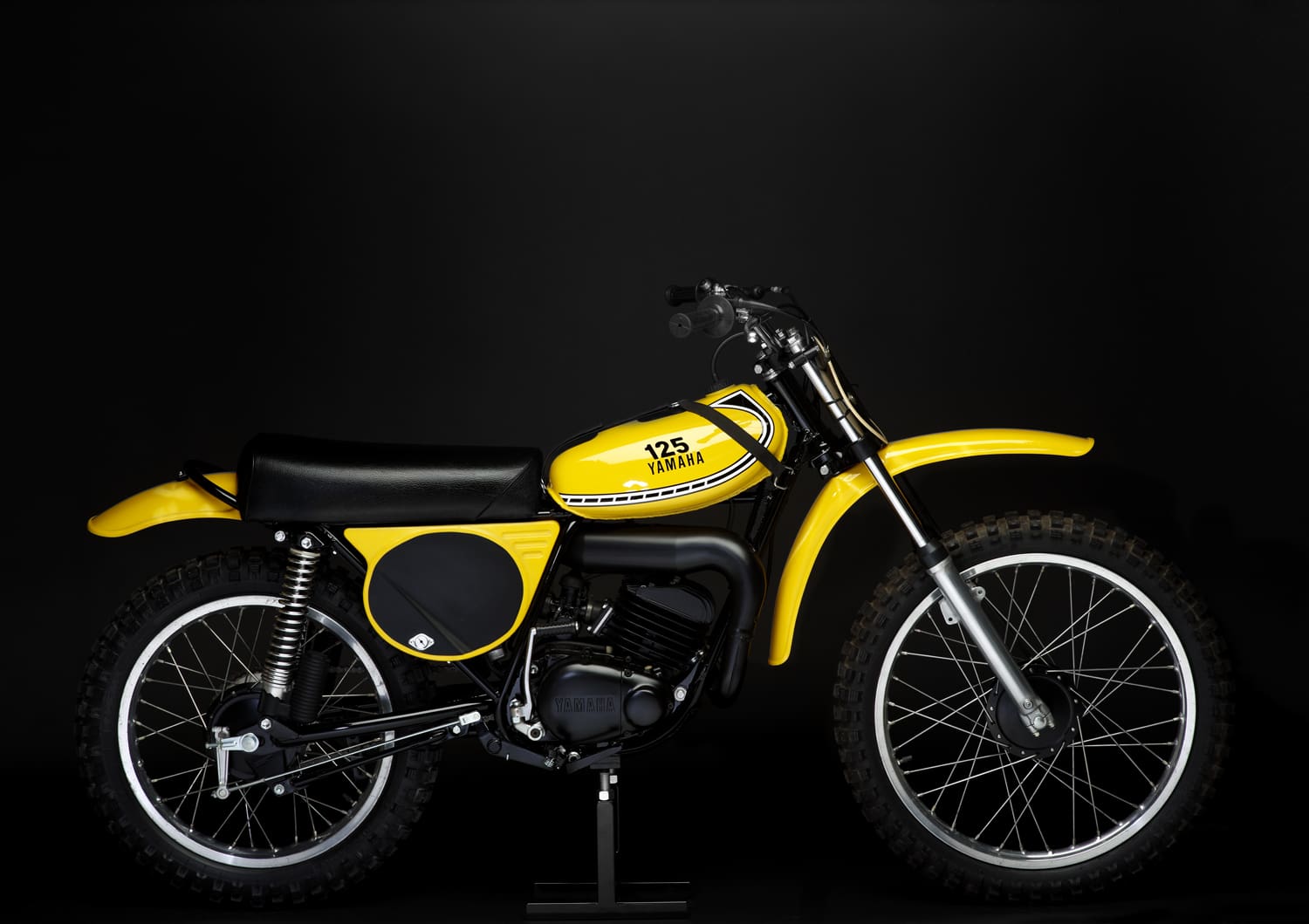 A yellow dirt bike sits on a black background.