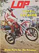 A vintage magazine cover showcasing a man riding a dirt bike, surrounded by antique MX books and aftermarket catalogs.