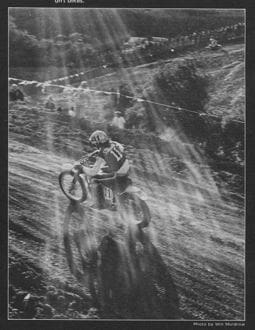 A vintage black and white photo of a dirt bike rider.