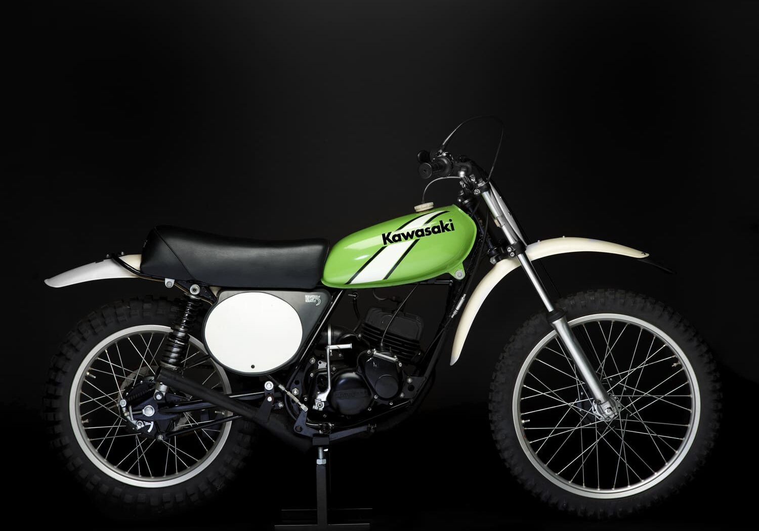 A green dirt bike is on display against a black background.